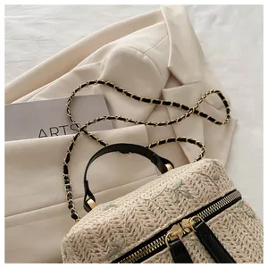 Top view of straw box bag featuring floral embroidery and elegant gold hardware