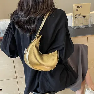 Chic golden crescent underarm bag with metallic mirror finish and sleek strap