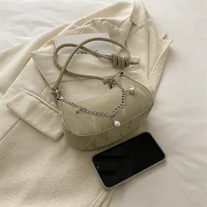 Light green marble crescent bag with silver chain and knot strap on beige blazer