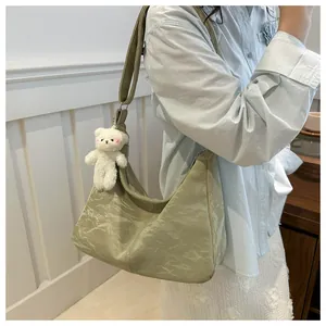 Detail view of sage green tote bag with unique pleated texture and cute plush bear charm
