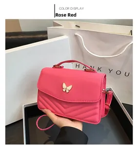 Detail of rose red crossbody bag with golden bow buckle and V-shaped quilted stitching