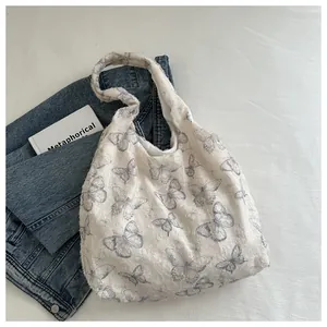 Close-up of white tote bag with gray butterfly patterns and tactile fringe texture