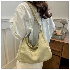 Detail of light green hobo bag featuring a unique wrinkled texture and wide shoulder strap