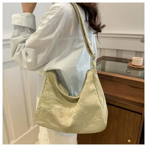 Detail of light green hobo bag featuring a unique wrinkled texture and wide shoulder strap