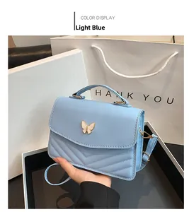 Detail of light blue crossbody bag with V-shaped quilting and butterfly clasp in gift box