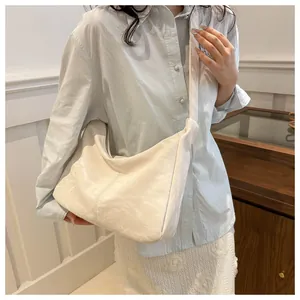 White large-capacity crescent hobo bag with pleated texture worn on a model's shoulder