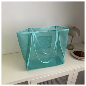 Detalle del bolso tote de malla verde menta con textura transparente y bolsillo interior