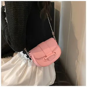 Détail du sac selle rose avec texture grainée et bandoulière en chaîne métallique