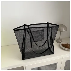 Detalle del bolso tote de malla negra con bolsillo interior y textura semitransparente