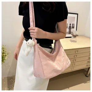 Close-up of pink pleated tote bag with a white teddy bear charm and soft strap