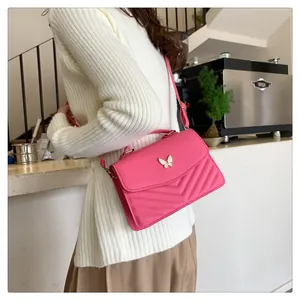 Detail of rose pink crossbody bag with butterfly buckle and V-shaped quilting detail