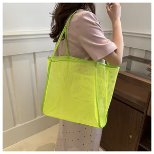 Detalle del bolso tote de malla verde neón que muestra su textura y asa de transporte