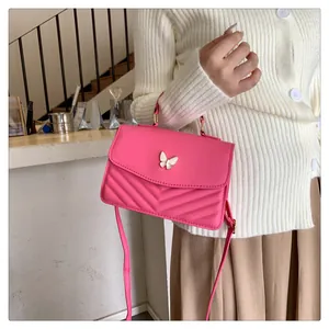 Detail of rose pink crossbody bag with V-quilted texture and white butterfly buckle