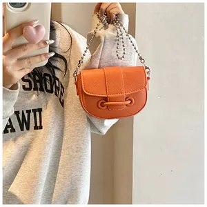 Détail du sac selle orange avec chaîne à billes argentée et cuir grainé lychee