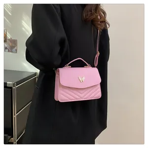 Detail of pink PU leather square bag with V-quilted pattern and white butterfly buckle