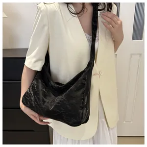 Detail of black pleated texture shoulder bag showing its glossy faux leather and large capacity