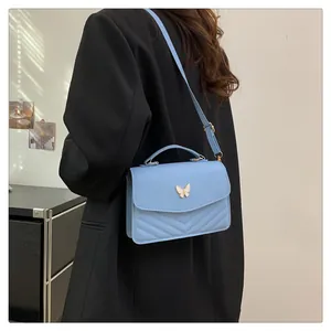 Close-up of light blue flap handbag featuring golden bow clasp and V-shape quilting details