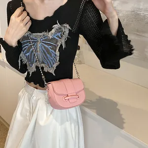 Sac bandoulière rose style selle avec chaîne perlée porté par un mannequin chic