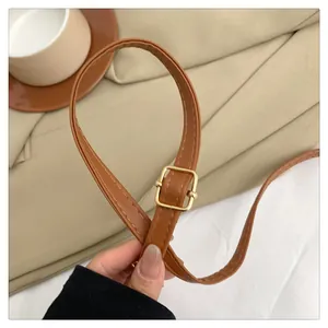 Detail of adjustable tan leather strap with premium gold metal buckle for shoulder bag