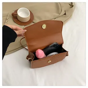 Brown quilted crossbody bag showing internal space with smartphone and cosmetics