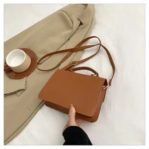 Detailed view of a brown PU leather crossbody bag on a white cloth with a blazer
