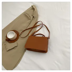 Close-up of caramel brown PU leather crossbody bag on professional blazer backdrop