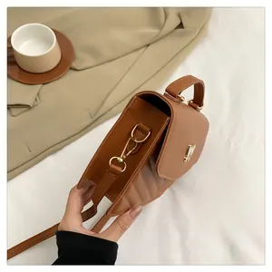 Detail of tan leather crossbody bag with quilted sides and elegant gold metal hardware