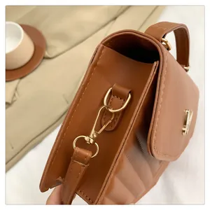 Detail view of brown PU leather crossbody bag with gold V-hardware and quilted pattern