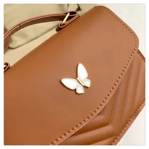 Close-up of brown leather handbag featuring golden butterfly clasp and V-quilted stitching