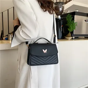 Stylish black women's crossbody bag featuring a white butterfly buckle and quilted texture