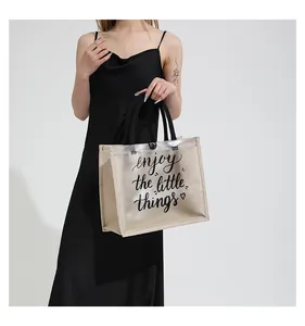 Detail view of transparent tote bag featuring enjoy the little things text and canvas trim