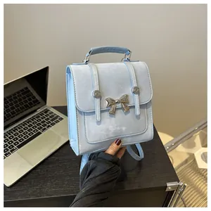 Detail of light blue bow handbag with silver butterfly clasp in a lifestyle office setting