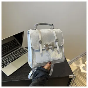 Detail of silver velvet backpack featuring metallic butterfly ornament and strap texture