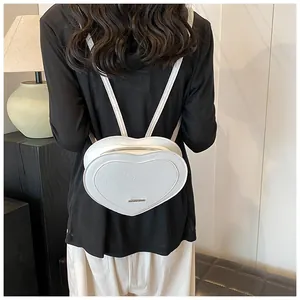 Detail of white heart-shaped mini backpack with embossed letters and metal zipper