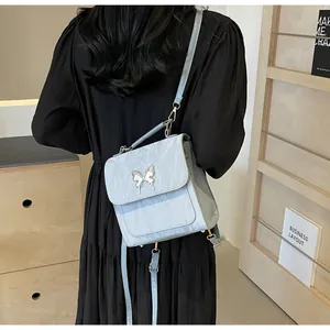 Back view of a light blue mini backpack with silver butterfly buckle on a black dress