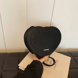 Close-up of heart-shaped black crossbody bag with rich rabbit letter embossing details