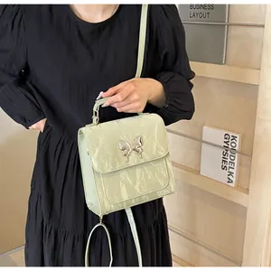 Detail of mint green crossbody bag featuring a shiny wrinkled texture and silver butterfly clasp