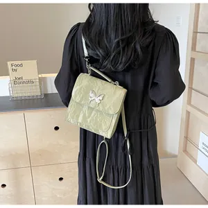 Detail of light green crinkle texture handbag featuring a silver metal butterfly buckle