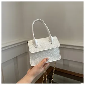 Mini sac bandoulière blanc avec texture litchi tenu à la main et chaîne dorée élégante