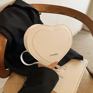 Detail view of heart-shaped cream PU bag with rich rabbit embossing and metal plate