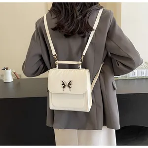 Detail of a creamy white glossy backpack with a black butterfly buckle on grey blazer
