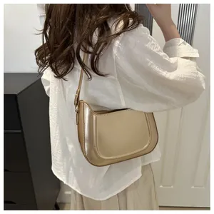 Champagne gold crescent shoulder bag with glossy finish shown on model in street style