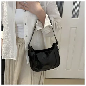 Detail of a chic black patent leather shoulder bag with a high-gloss finish for women