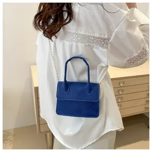 Détail du mini sac bleu foncé en cuir grainé avec une fine bandoulière dorée