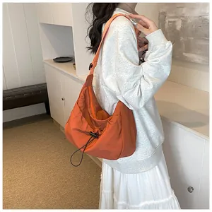 Detail of orange nylon hobo bag featuring functional drawstring and adjustable strap