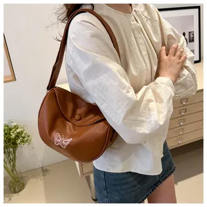 Dettaglio della borsa in pelle PU marrone con ricamo a farfalla bianca di tendenza