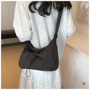 Detail view of the black nylon crossbody bag featuring a drawstring texture and wide strap