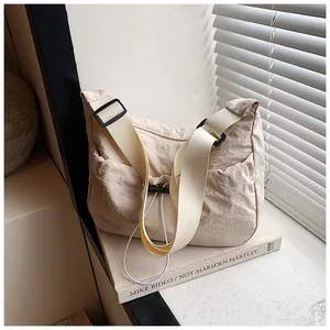 Detail of light beige crossbody tote bag with adjustable drawstring pocket and strap