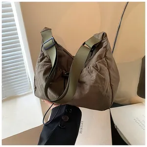 Detail of a dark khaki pleated nylon crossbody bag with an adjustable wide shoulder strap