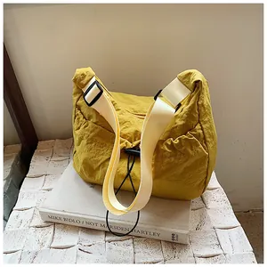 Detail of bright yellow pleated tote bag with white strap and black drawstring accent